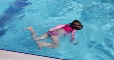 Mutlu çocuk güneşli bir tatil gününde havuzda yüzmeyi öğreniyor. Çocuklar tatil ve dinlenme