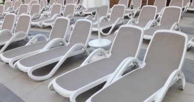Boş güneş şezlongları ve güneş şezlongları sıraya dizildi. Tatilciler için konforlu hizmet