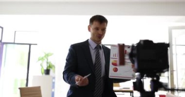 İş vlog 'u, video koçluğu ve analitik sunumu. Kameraya finansal istatistikler gösteren kendinden emin akıllı erkek uzman