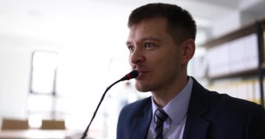 Motivasyon konuşmacısı sahnede mikrofonla konuşuyor. Konferansta akıl hocası ve topluluk önünde konuşma