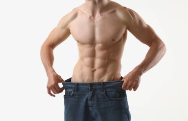 Kaslı, formda bir adama yakın çekim, ne kadar büyük pantolon, ince vücut, mükemmel vücut. Spor hocası, profesyonel model. Spor, modellik, sağlık konsepti