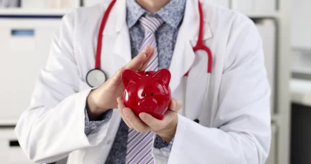 Lekarz Białym Płaszczu Głaszczący Czerwoną Świnkę Koncepcja Ubezpieczenia Medycznego — Wideo stockowe