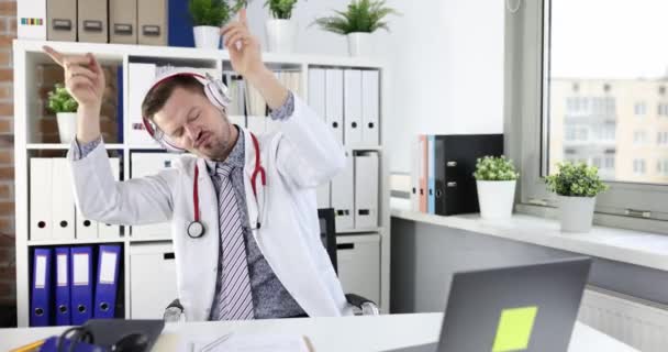 Ung Manlig Läkare Hörlurar Dansar Arbetsplatsen Kliniken Positiva Känslor Läkare — Stockvideo
