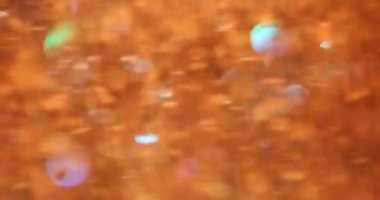 Yıldızların soyut arkaplanlı turuncu altın parıltı bokeh. Siyah arka planda uçuşan turuncu ışıltılar