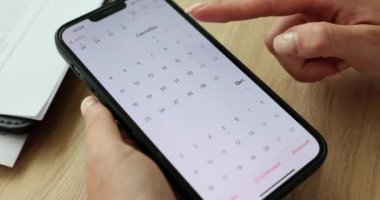 İş kadını akıllı telefon ekranına işaret ediyor ve uygulamadan takvimi kontrol ediyor. Ekrandaki uygulama ve grafik programında oluşturuldu