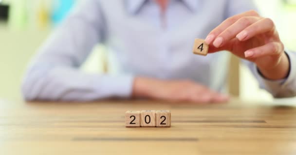 数字2024は木製の立方体で構成されています 女性の手は202を指で番号2024に変えました — ストック動画