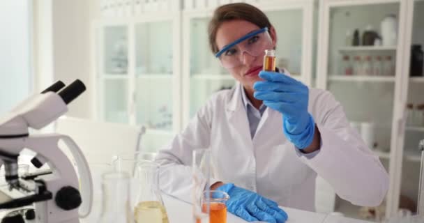 研究室の液体の化学分析のためのガラス瓶を探して保持する科学者 実験室および有毒液体の化学装置を使用している科学者 — ストック動画