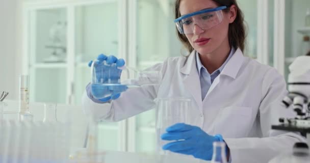 科学者はフラスコから医学研究室のガラスに水を注ぎます 実験室での水質テスト — ストック動画