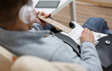 Evde erkek el oynayın ve elektro gitar müzik yapan melodi müzik notasyon büyük kavramı closeup zevk dinleme fark eder