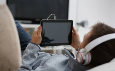 Erkek el, koltukta oturup internette sörf yaparken tablet tableti tutuyor. Uygulamayı kullanarak boş zamanlardaki müzik konseptini kapatıyoruz..