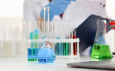 Mavi mor sıvı laboratuvar tüplü kimya endüstrisi ampulü laboratuvardaki masanın üzerinde duruyor. Sıvı test geliştirme maddeleri zehir dengeleyiciler ev temizliği.