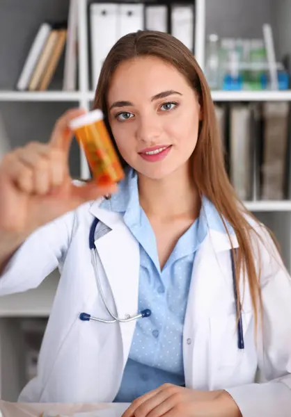 Beautiful smiling female doctor hold in arms pill bottle and offer it to visitor portrait. Panacea or life save antidepressant from legal store prescribe vitamin medic aid for healthy lifestyle