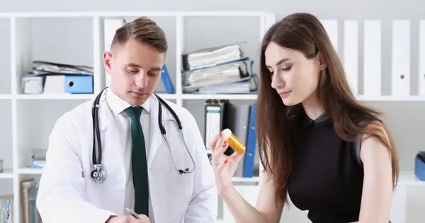 Handsome male doctor explain prescription while patient hand hold jar of pills. Panacea and life save prescribe antidepressant legal drug store vitamin aid give or take pills ward round concept