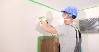 Yetenekli işçiler alçı duvarı elektrikli zımpara makinesiyle cilalarlar. Usta ofiste tamirat yapıyor.
