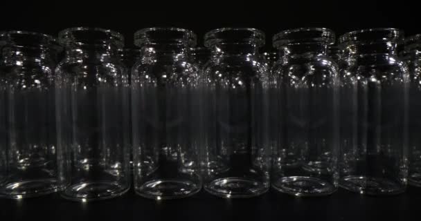 空玻璃瓶的疫苗和药品在黑色背景上排成一排 医疗用品用专业玻璃器皿 — 图库视频影像