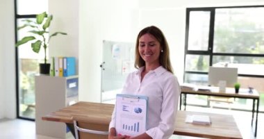 Elinde grafikler ve istatistiklerle gülümseyen güzel kadın pazarlamacının portresi. Belgelendirme ve hesaplama