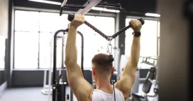 Adam kaslarını çalıştırıyor ve spor salonunda güç egzersizleri yapıyor. Atlet yeni simülatör ekipmanlarıyla antrenman yapıyor