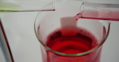 Üniversite deneysel bilim adamı cam şişeyle kırmızı kimyasal çözeltiyi karıştırıyor. Laboratuvarda kırmızı ve sarı zehirli sıvılar
