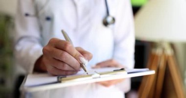 Kadın dosyasına kalemi olan bir doktor yazmış, yakın plan. Hasta tıbbi verileri, ambulans resepsiyonu.