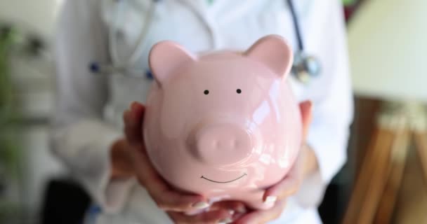 Kobieta Lekarz Różową Świnką Rękach Zbliżenie Drogie Procedury Medyczne Inwestycje — Wideo stockowe