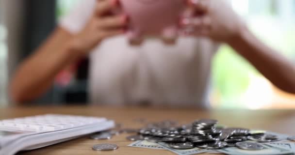 テーブルの上にコインと貯金箱 クローズアップと計算機です 家族の予算の概念 収入と費用 — ストック動画
