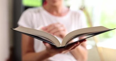 Kadın, kitabın sayfalarıyla ayakta duruyor, yakın plan. Okuma literatürü, kütüphane kavramını