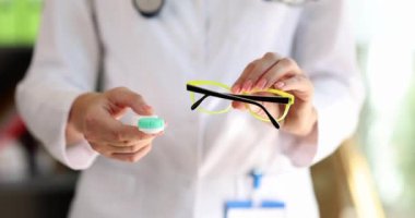 Kadın bir doktor. Gözlük ve kontakt lens tutuyor. Yakın plan. Görüş için aksesuar seçimini kavra