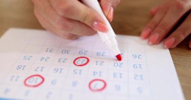 Bir kadın takvime kırmızı sayılar çizer, yakın plan, yüzeysel odaklanma. Kavram gündemi, önemli tarih