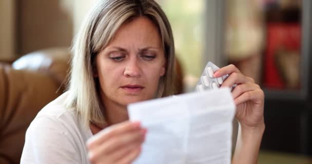 一个拿着药丸的女人仔细阅读指令 一个特写 慢动作 概念节育 有缺陷的药物 — 图库视频影像