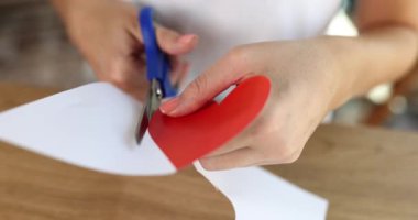 Kadınların elleri, kalplerinin makasıyla kağıttan kesilir. Yakın plan, yavaş çekim. Kartpostalı destekle, aşkım.