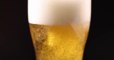 Altın bira köpüklü bardağa doluyor ve birçok gaz kabarcığı 4K 'lık filmi yavaş çekimde kapatıyor. Alkol bağımlılığı kavramı