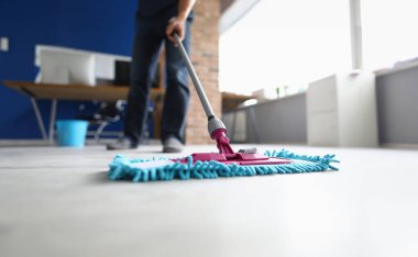 Ofiste yerleri paspaslayan bir adam var. Temizlik şirketi hizmetleri kavramı