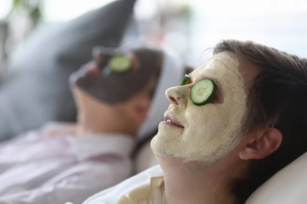 Cosmetic mask was applied to both male and female faces and cucumber slices on eyes. Rejuvenating facial treatments concept