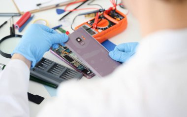 Master atölyede cep telefonunun kapağını açıyor. Cep telefonu arızası teşhis konsepti