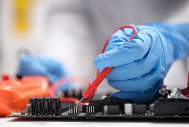 Usta tamirci, anakart üzerinde dokunmatik yakın çekim ile test ediyor. Bilgisayar donanımı ve elektronik konseptinin onarımı ve bakımı