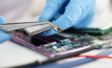 Atölyede kırık telefonun üzerinde mikroçip tutan lastik eldivenler ustası. Cep telefonu tamir kavramı