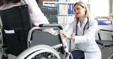 Woman patient sitting in wheelchair discussing x-ray with doctor. Spinal injury and rehabilitation of the disabled