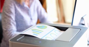 Secretary prints on printer financial indicators of analytics in charts. Preparation of statistics in marketing concept
