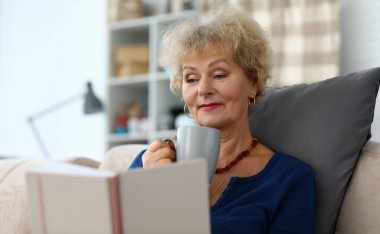 Kitap okuyan ve bitki çayı içen yaşlı kadın Agailnst 'in arka plan portresi. Rahatlama ve beyin eğitimi zevk kavramı