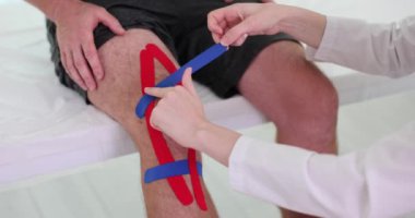 Fizyoterapist klinikteki hastanın dizine Kinesio bandı yapıştırıyor. Diz sakatlığı ve tedavi