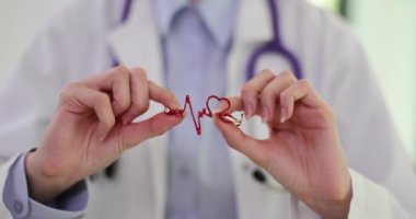 Doktor kardiyolog kırmızı kalp ikonunu elinde tutuyor. Kalp ve damar hastalıkları semptomlara neden olur