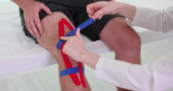 Fisioterapista Applica Nastro Kinesio Ginocchio Del Paziente Clinica Lesioni Trattamenti — Video Stock