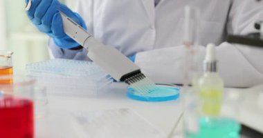 Pipette örnekleri derin kuyu tabakasına. Laboratuvarda mavi sıvı üzerine çalışma