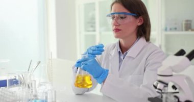 Kimyager bilim adamı cam şişenin içindeki sarı kozmik yağ ve sıvı maddenin kokusunu alıyor ve laboratuvarda deney yapıyor. Bilimsel araştırma çalışmaları ve aromaterapi araştırmaları