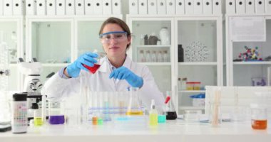 Biyokimyasal tıbbi laboratuvar araştırması, kırmızı sıvı ve test tüpleriyle çalışan laboratuvar uzmanı. Zehirli kimyasal sıvılar üzerine çalışmalar