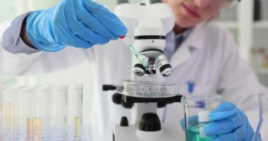 Bilimadamı laboratuvar kapanışında pipetten mavi sıvıyı cama atıyor. Laboratuvarda zehirli çözücüler test ediliyor.