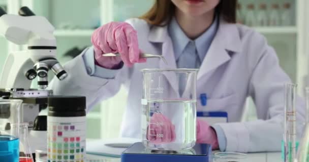 研究室の科学者は水に溶解したカリウムの過マンガン酸を投げます 一貫性を修正するために希釈カリウムの過マンガン酸塩 — ストック動画