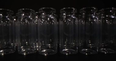 Siyah zemin üzerinde aşı üretimi ve ambalajı için kullanılan boş cam şişeler. Tıbbi cam eşyalar.