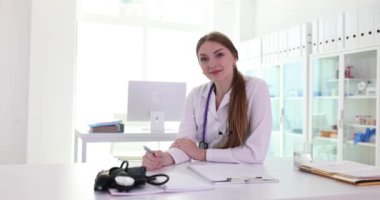 Klinikteki iş yerinde gülümseyen genç bayan doktorun portresi. Terapist hemşire veya kardiyolog ve tıbbi bakım ve sigorta