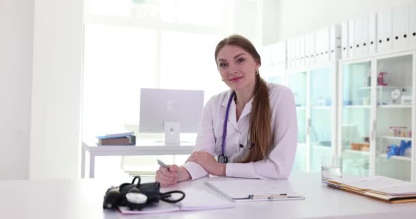 クリニックの職場で笑顔の若い女性医師の肖像画 セラピスト看護師 心臓科医 医療保険 — ストック動画